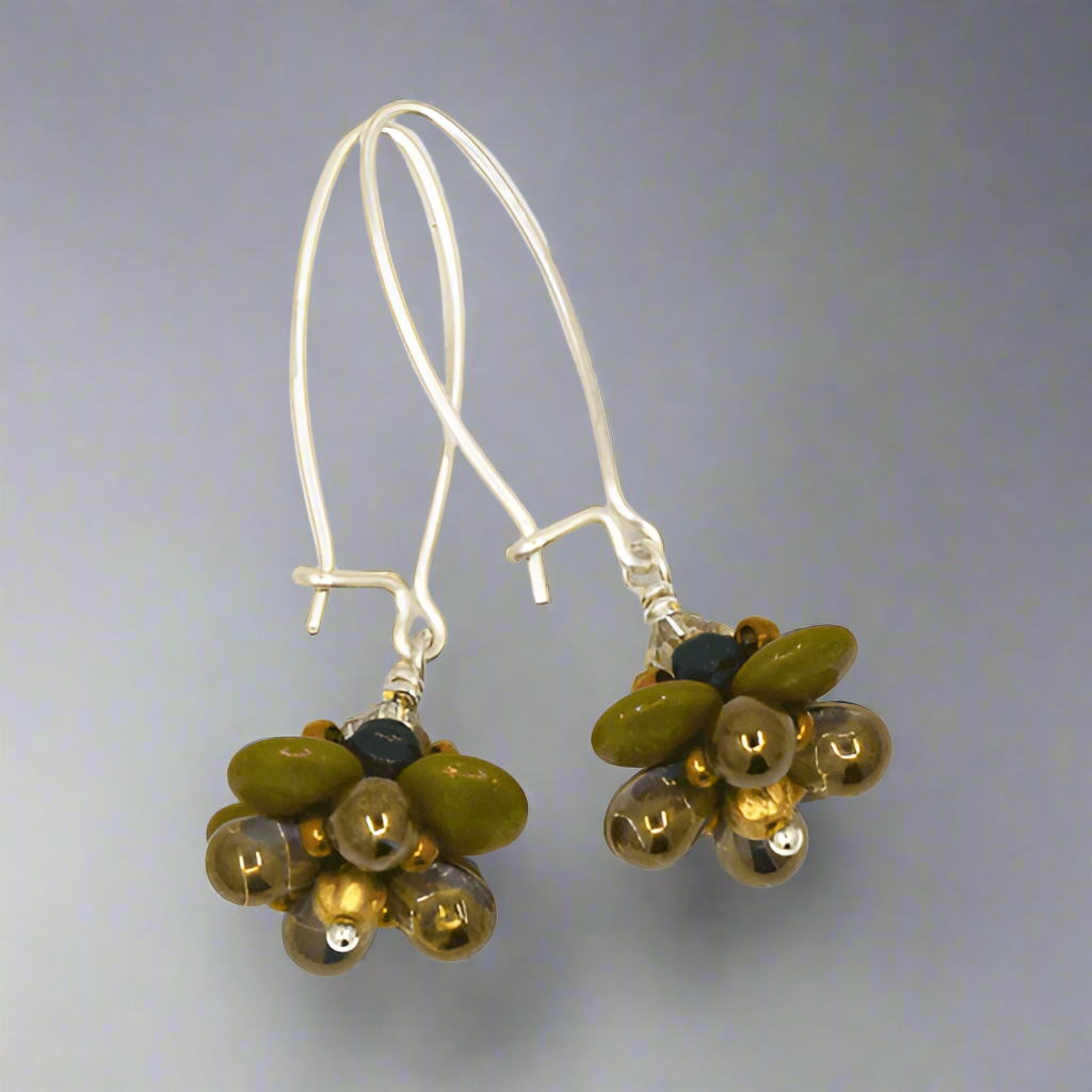 A pair of silver and translucent teal earrings against a gray background. The earrings have long silver oval wires that latch and the dangling parts are beaded flowers that have avocado green petals and bronze accents.