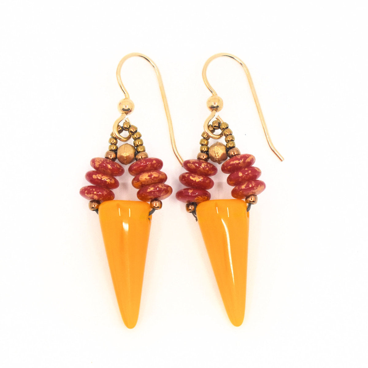 Earrings formed from warm yellow upside down cones suspended from two parallel stacks of red discs on top lay on a white background.