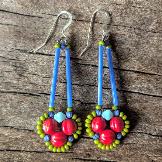 Long earrings with red, green and blue beads on a wooden surface.
