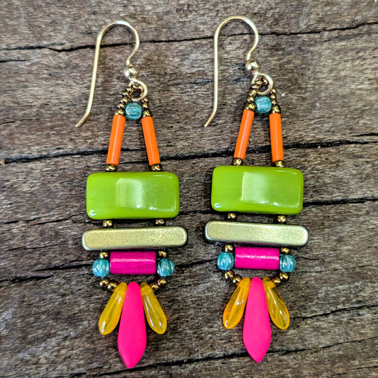 Colorful earrings with green, pink, orange, and yellow beads on a wooden surface