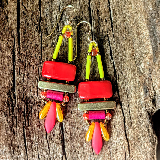 Colorful beaded earrings with red, pink, orange and yellow components on a wooden surface