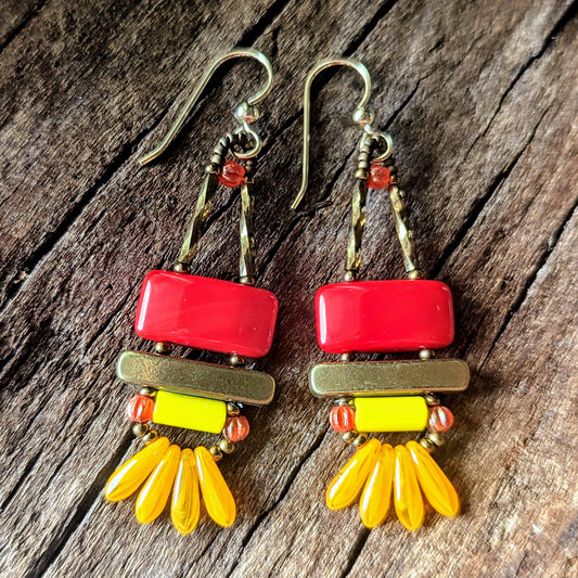 Colorful earrings with red, yellow, and gold elements on a wooden surface