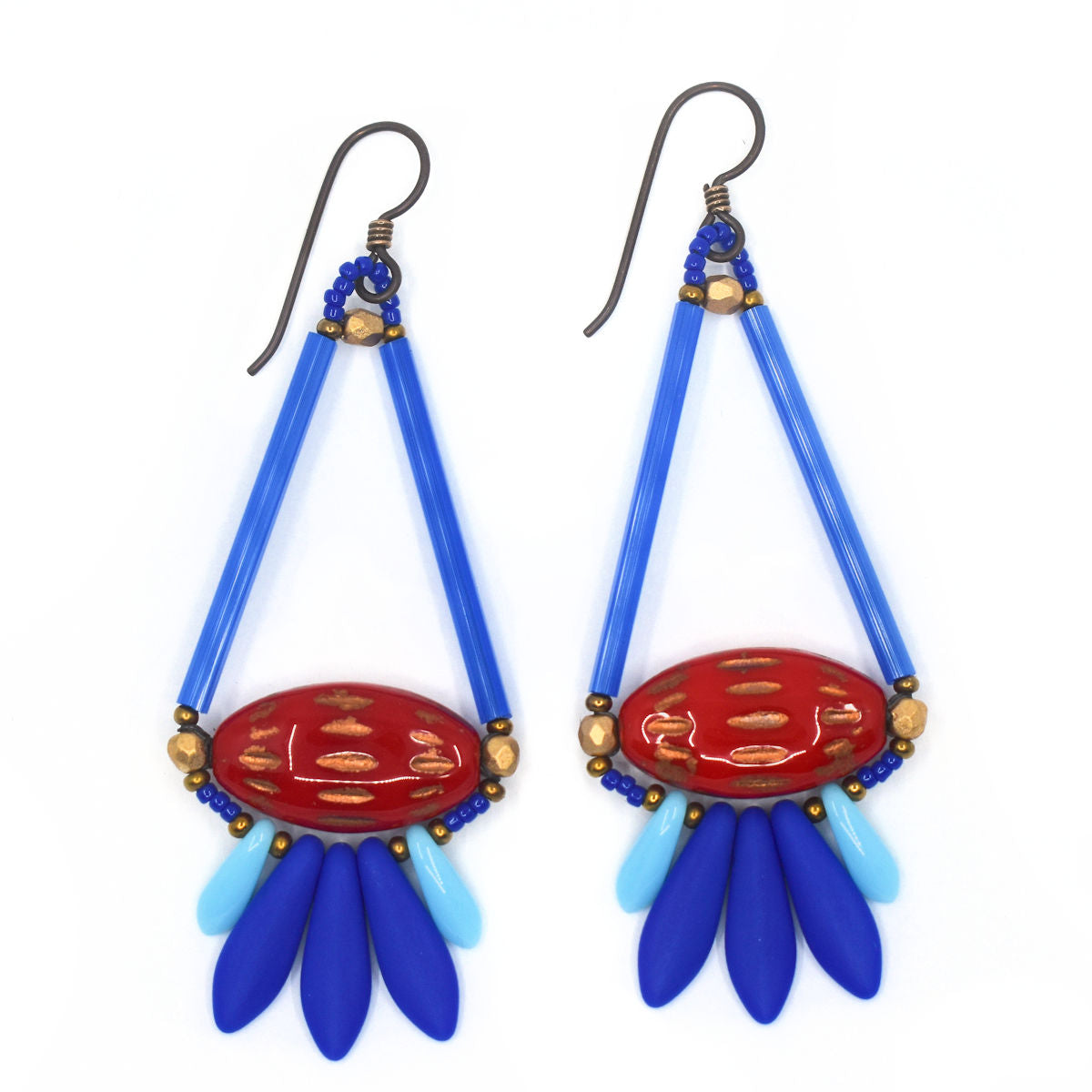 Long blue and red earrings shaped like a teardrop with tail feathers lay on a white background. The upper part of the teardrop shape is formed by long medium blue tubes. At the base is a glossy red pointed oval with copper horizontal dashes. At the bottom is a spray of dagger shaped beads, the center three are matte medium blue and the outer two are shiny and light blue. The earrings have dark ear wires.