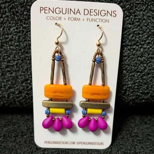 Colorful orange, yellow and fuchsia earrings on a Penguinia Designs card against a dark textured background
