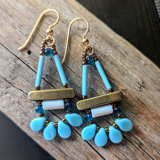 Pair of earrings with blue and white beads on a wooden surface
