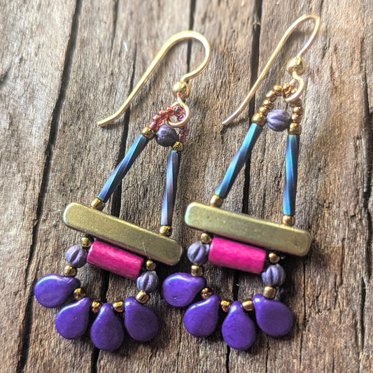 Colorful beaded earrings with purple and pink components on a wooden surface