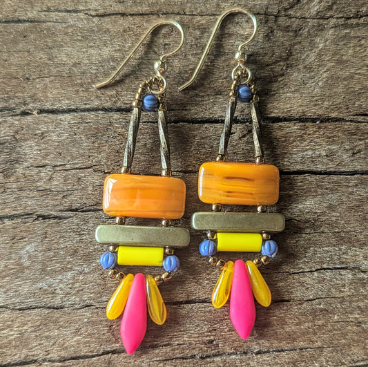 Colorful earrings with orange, yellow, pink, and blue beads on a wooden surface